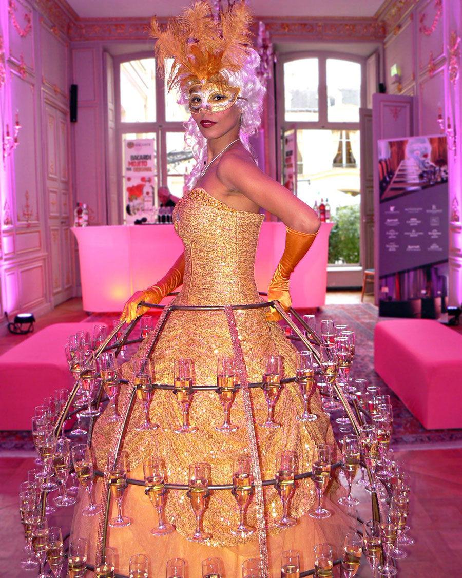 Hôtesse en robe à champagne dorée accueillant les invités